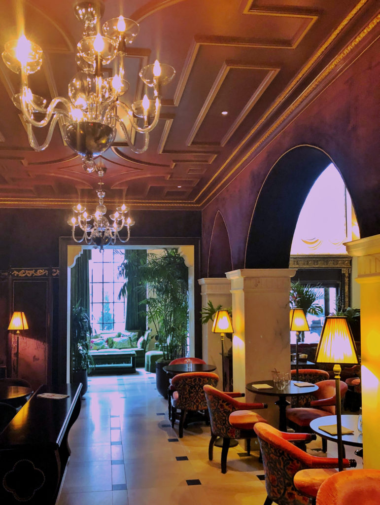 New traditional interior design style - Lounge at the Nomad hotel with plum arched walls and glass chandeliers.