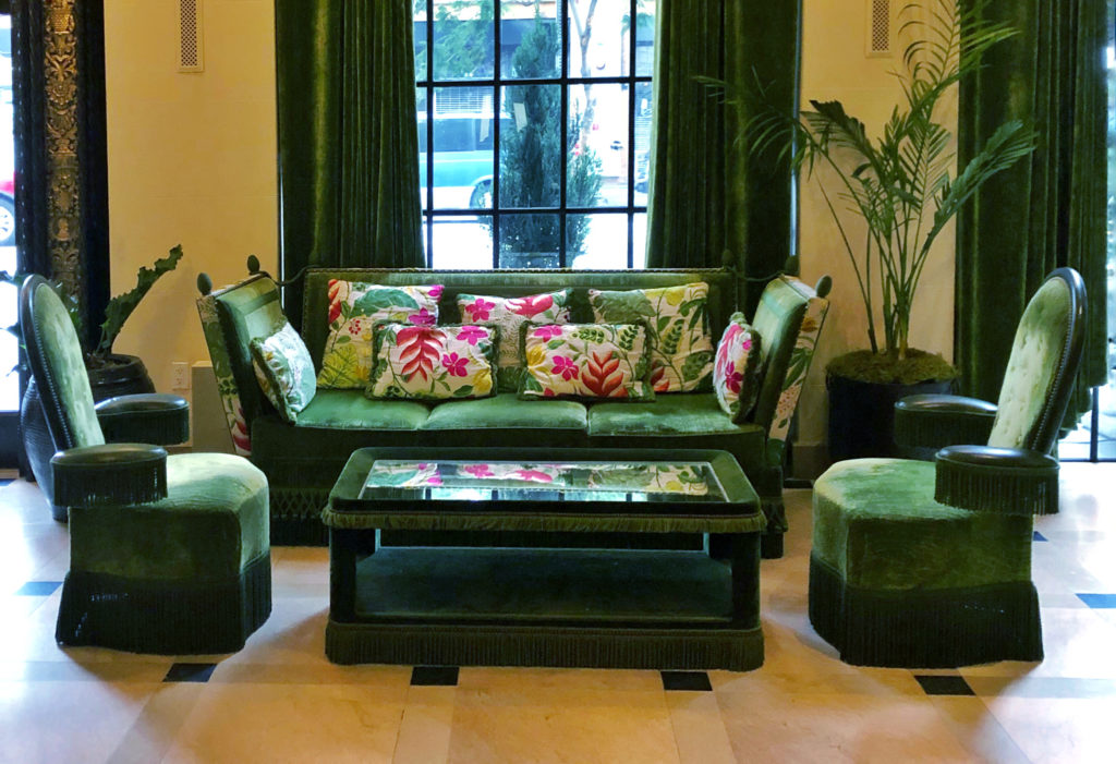 New traditional interior design style - Emerald green velvet sofa and lounge chairs with fringe and colorful throw pillows.