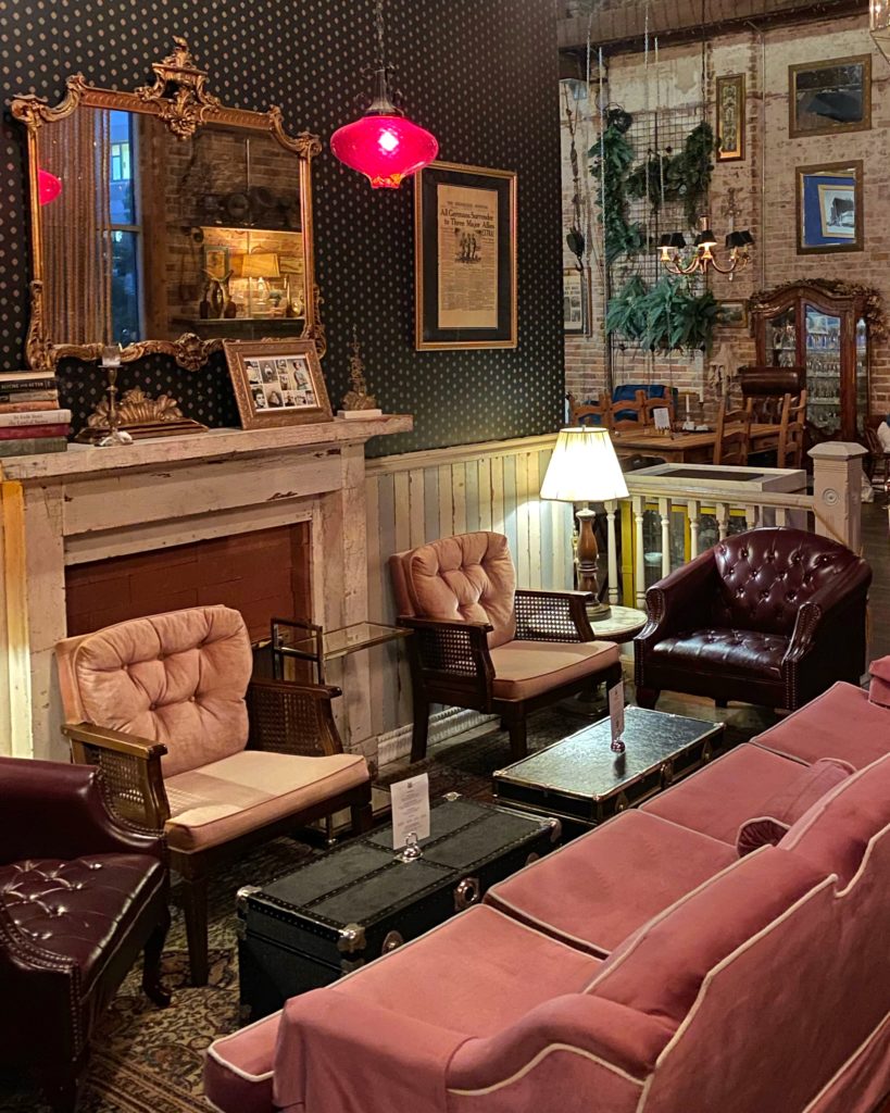 Speakeasy interior design style - Pink plush furniture arranged around a vintage fireplace at Mathers in Orlando.