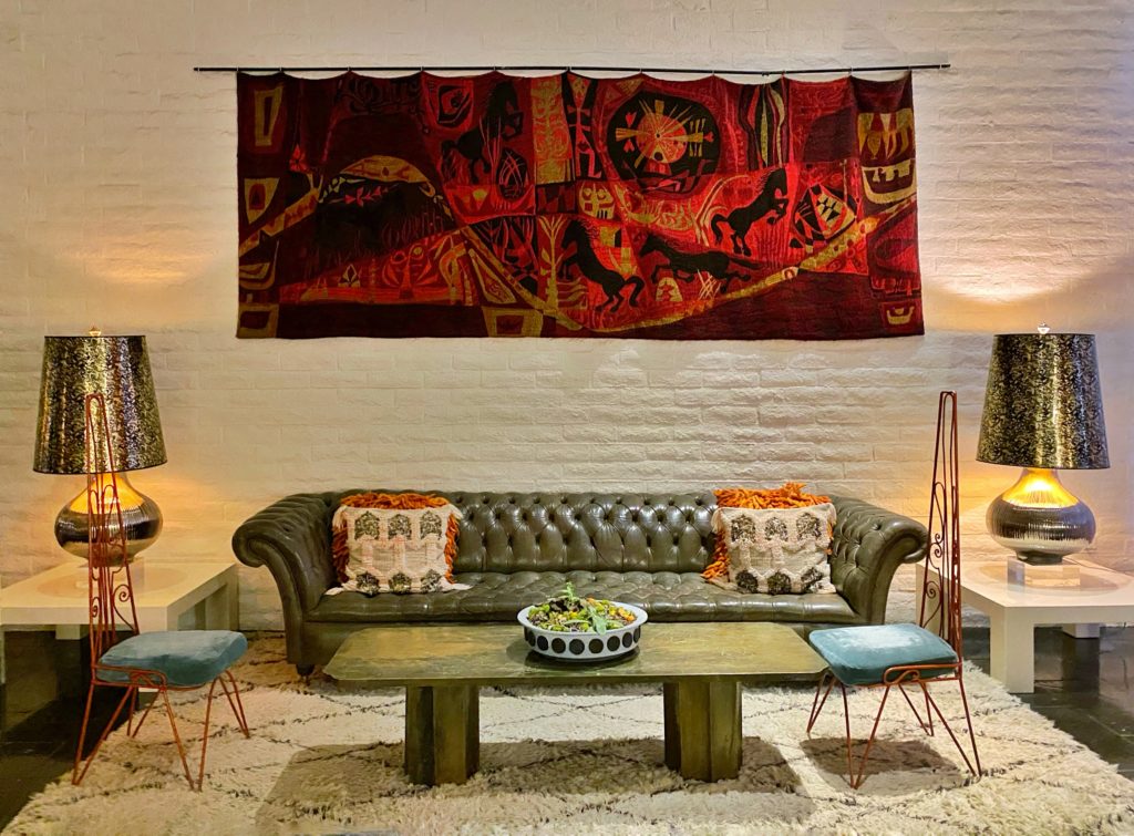 Bohemian living room with sofa, coffee table, artwork, and table lamps at the Parker Palm Springs.