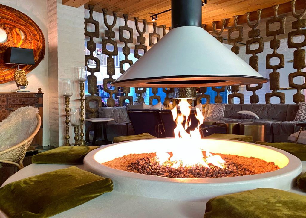 Cozy circular fire pit lounge with Bohemian decor at the Parker Palm Springs hotel.
