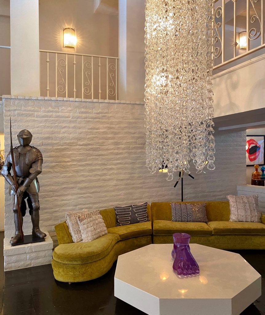 Funky, eclectic Boho decor at the Parker Palm Springs includes knight in armor sculpture, a purple glass foot, and a glass link chandelier.