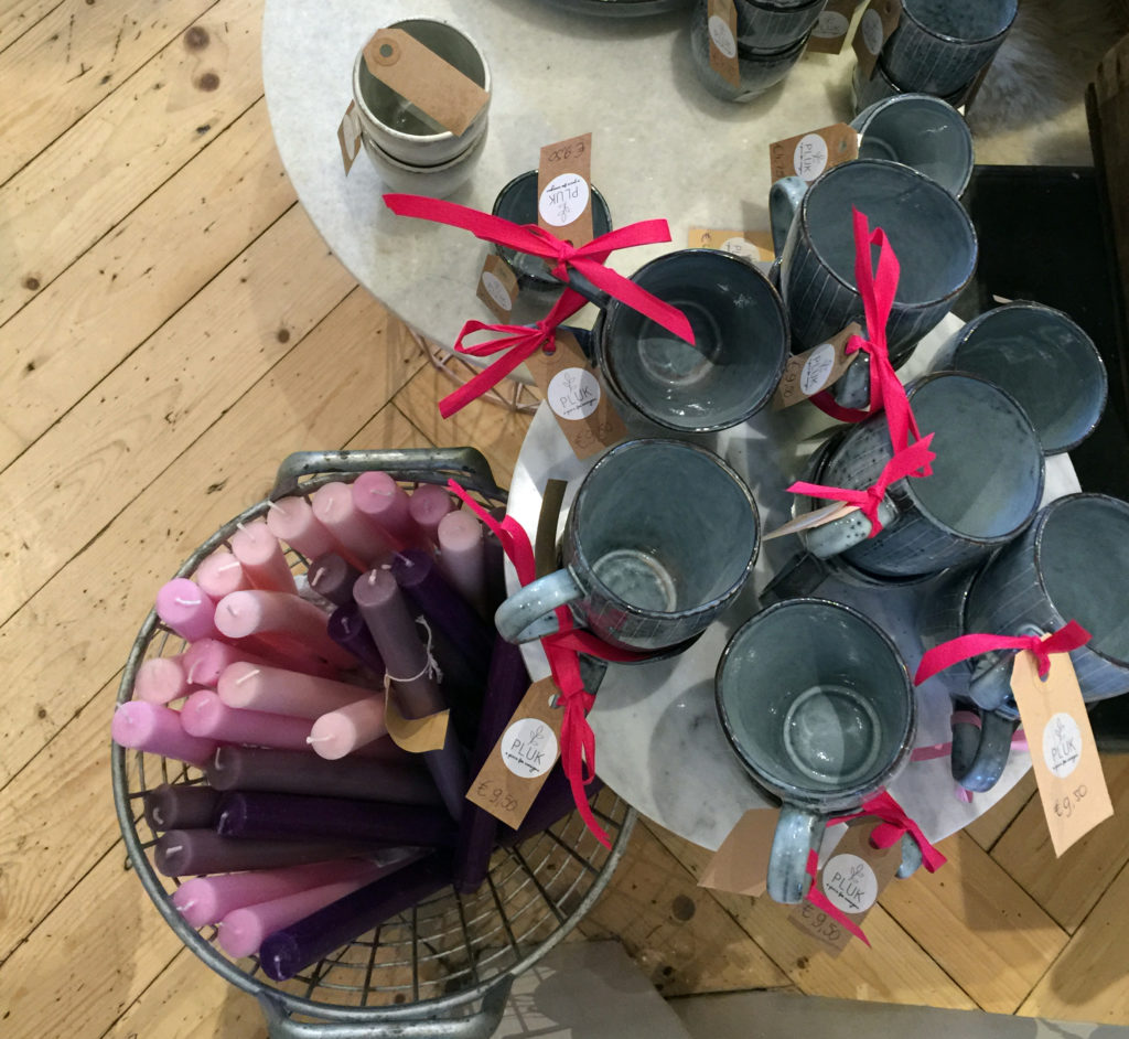 Assortment of lavender and purple candles and glazed ceramic mugs for sale at Pluk, a boho cafe.