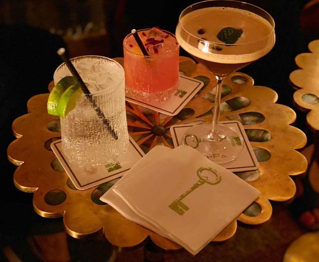 Three cocktails displayed on a scalloped brass coffee table.