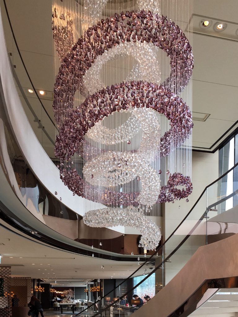 Luxe interior design style featuring dramatic hanging glass chandelier with layers of purple cascading crystals.