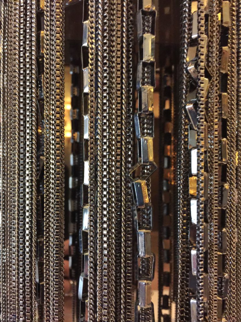 Series of metal chains and linked metal in a polished stainless steel finish.