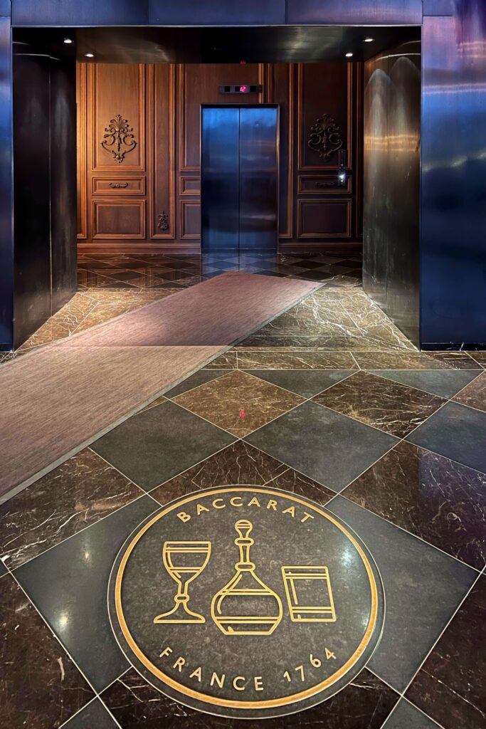 The Baccarat logo and emblem grace the threshold at the entrance inside the Baccarat Hotel lobby in New York City.