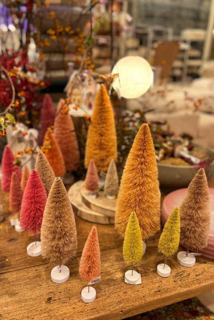 Collection of bottle brush Christmas tree decor display on rustic wood table. Merchandising from ABC Carpet and Home in Manhattan.