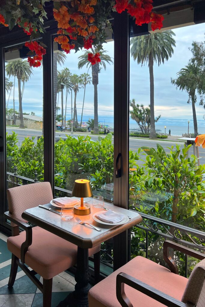 Dining table under colorful flowers overlooking the ocean at the Terrace restaurant at the Georgian Hotel in Santa Monica.