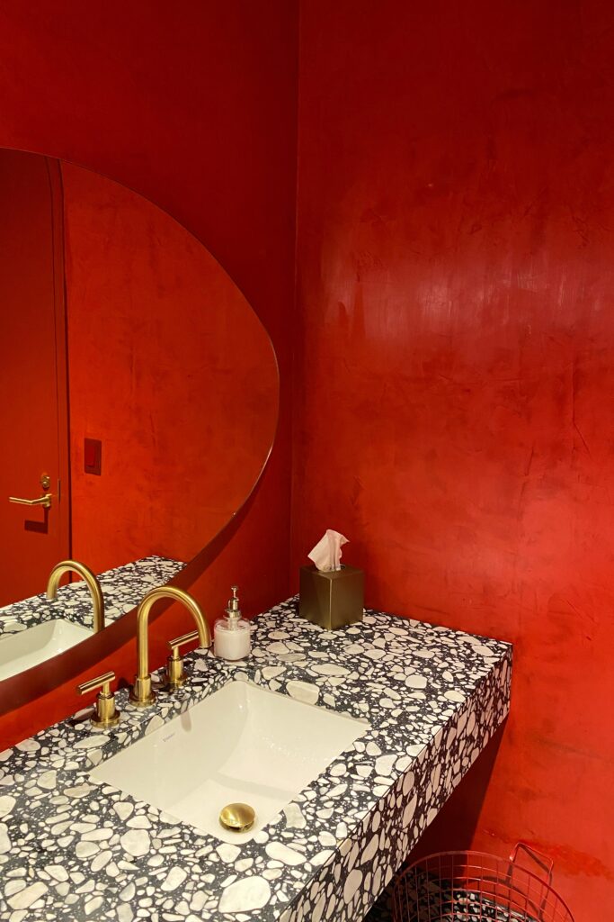 Bright red restroom and terrazzo vanity in the Virgin Hotel in Dallas, Texas.