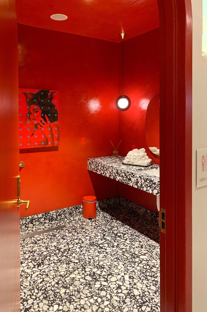 Bright red restroom and terrazzo tile in the Virgin Hotel in Dallas, Texas.