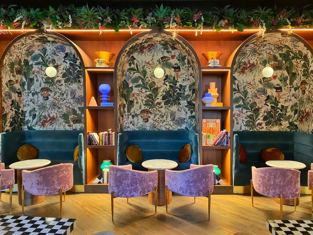 Dopamine Decor patterned wallpaper at the 3 arched niche seating areas at the Funny Library coffee shop at the Virgin Hotel in Dallas, Texas.