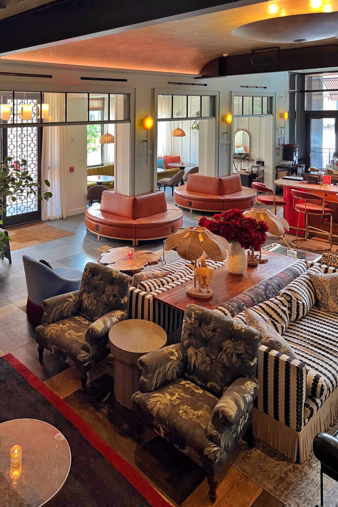 Lobby at Virgin Hotel New Orleans featuring circular leather banquettes, mix of eclectic patterned seating, rattan lamps, and rich wood accents