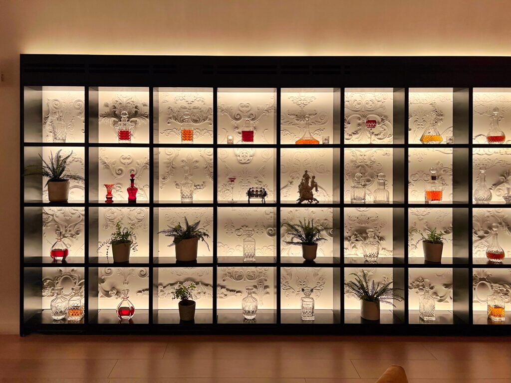 View of luxury backlit bookshelf and decanters inside the Edition Hotel in Times Square, New York City. Shelf styling inspired by luxury hotels.