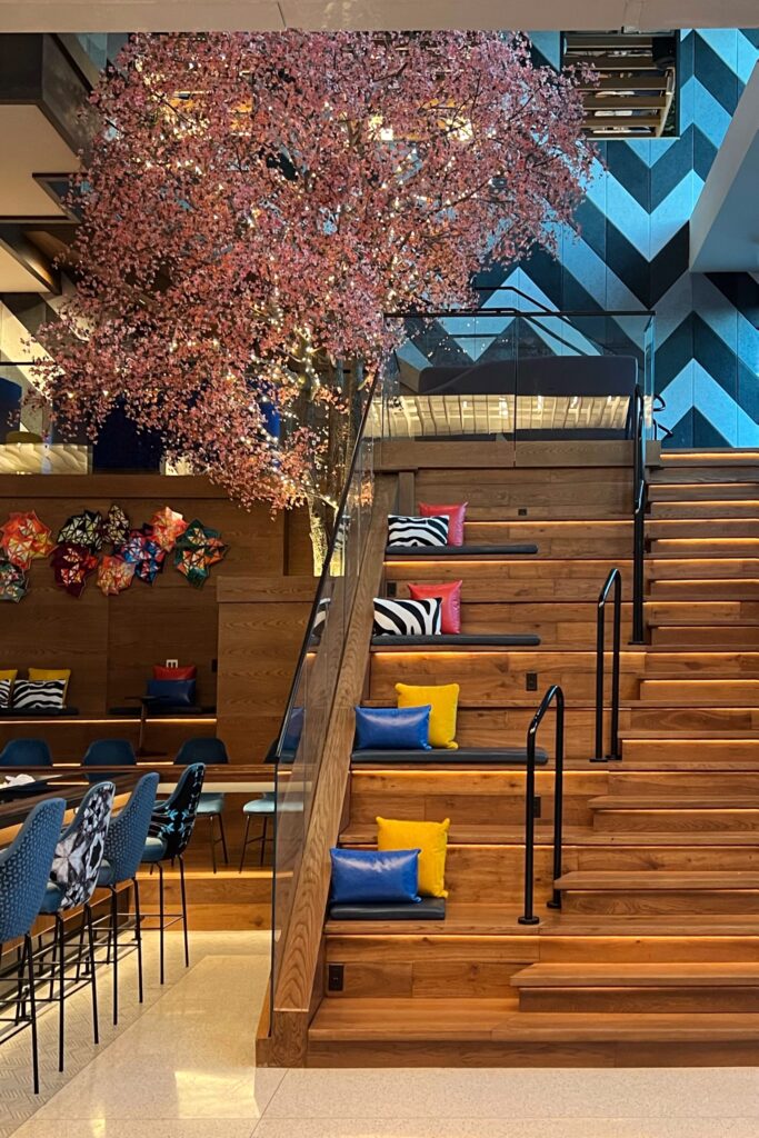 View of amphitheater style seating and a pink tree inside the lobby of the Wave Hotel in Orlando, Florida.