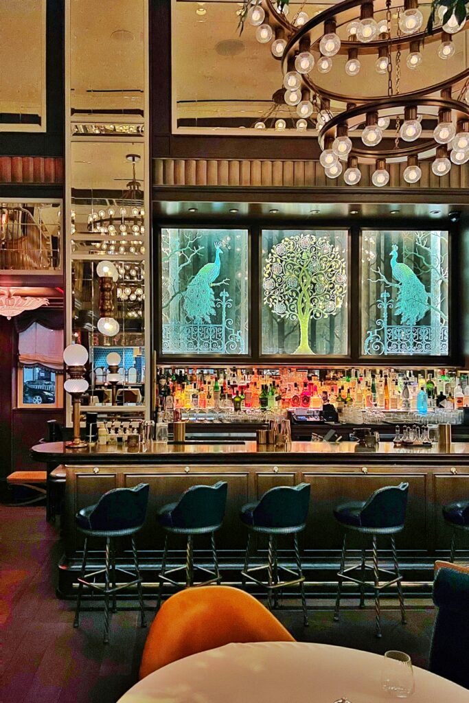 Aesthetic Travel Guide to New York City - Cafe Carnellini liquor display at the bar with backlit glass peacock artwork.