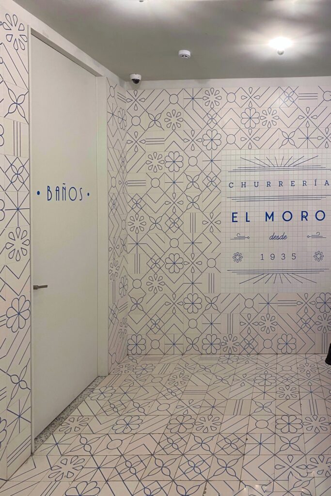 Patterned blue-and-white tiled interior at El Moro Churrería in Mexico City, featuring geometric and floral motifs with signage marking its historic founding in 1935.