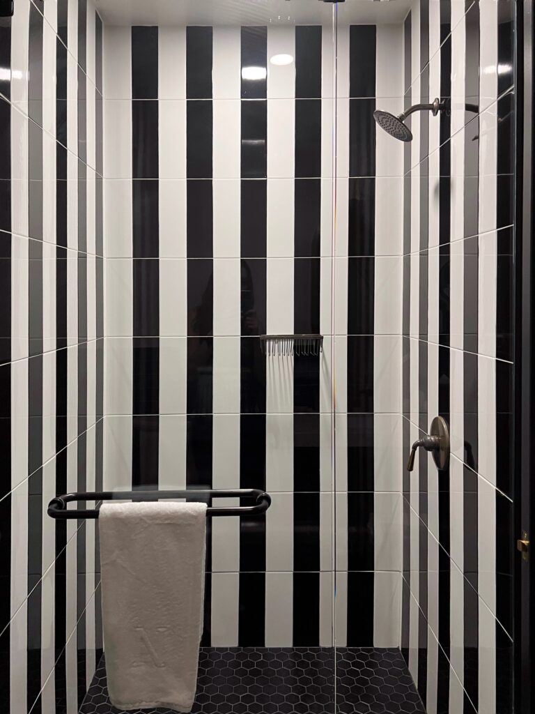 Dream Hotel Nashville bathroom with bold black and white striped shower tile — chic design inspiration featured in the Nashville Aesthetic Travel Guide.