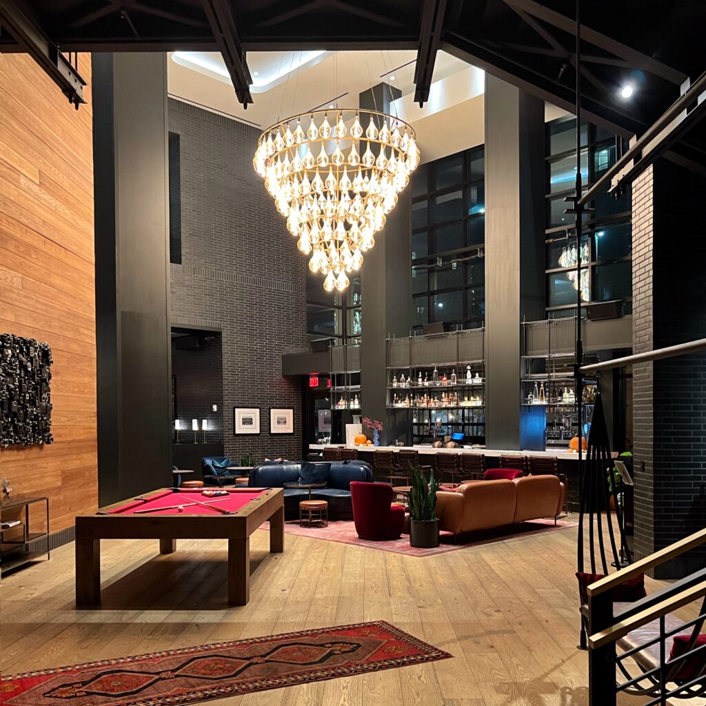 The Commons Club at Virgin Hotel Nashville featuring a dramatic chandelier, modern bar, pool table, and stylish lounge seating — highlighted in the Nashville Aesthetic Travel Guide.