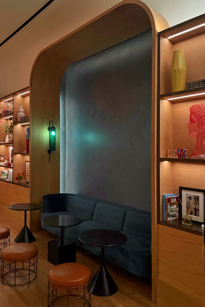 Cozy lobby seating nook at Virgin Hotel Nashville with velvet sofa, sculptural tables, and curated art shelves — stylish detail featured in the Nashville Aesthetic Travel Guide.