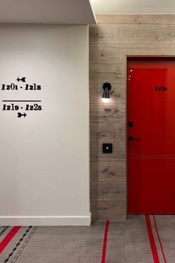 Bold red guest room door with modern signage and playful corridor design at Virgin Hotels Nashville, a trendy boutique hotel featured in the Nashville Aesthetic Travel Guide.