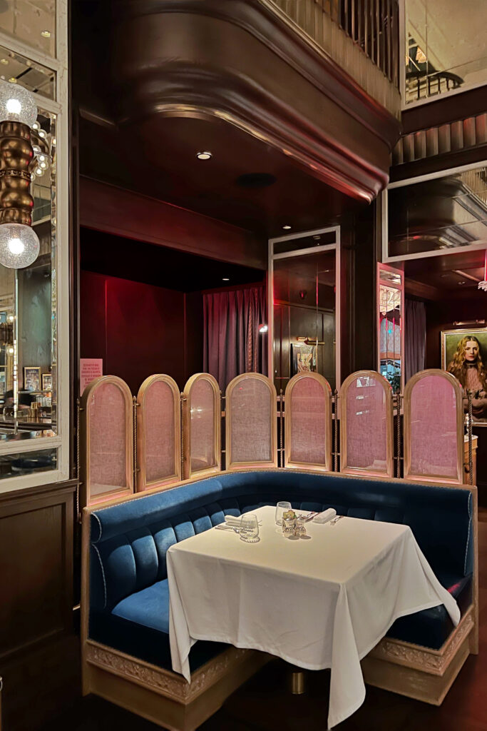 Modern Art Deco style speakeasy-style booth at Café Carmellini in New York City, featuring deep blue velvet seating, brass accents, and modern Art Deco interior design that creates a romantic, sophisticated dining atmosphere.