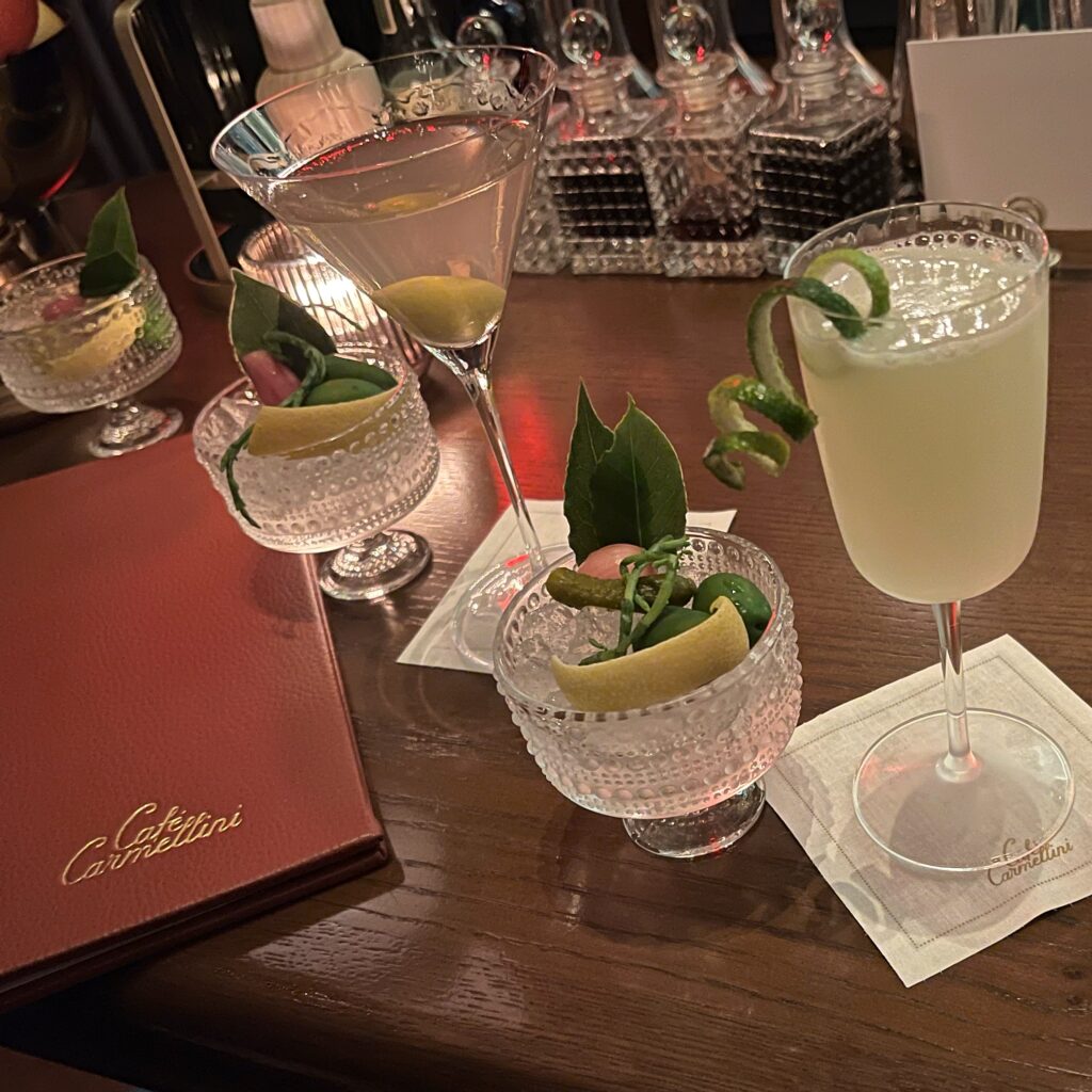 Art Deco–inspired cocktails at Café Carmellini in New York City, served in elegant glassware on a polished wood bar — a modern speakeasy–style experience blending design and fine dining.