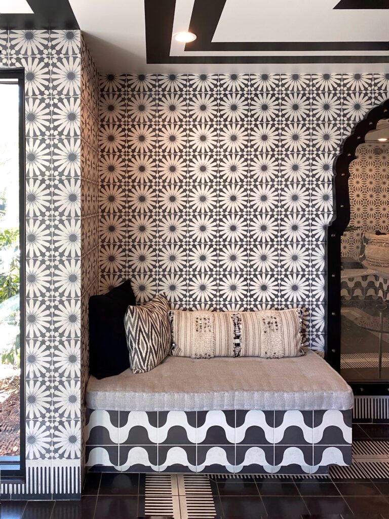 Black and white Moroccan-inspired tile nook at the Sands Hotel in Palm Springs - Indian Wells, featuring patterned walls, geometric floor tiles, and a cushioned bench with textured pillows.