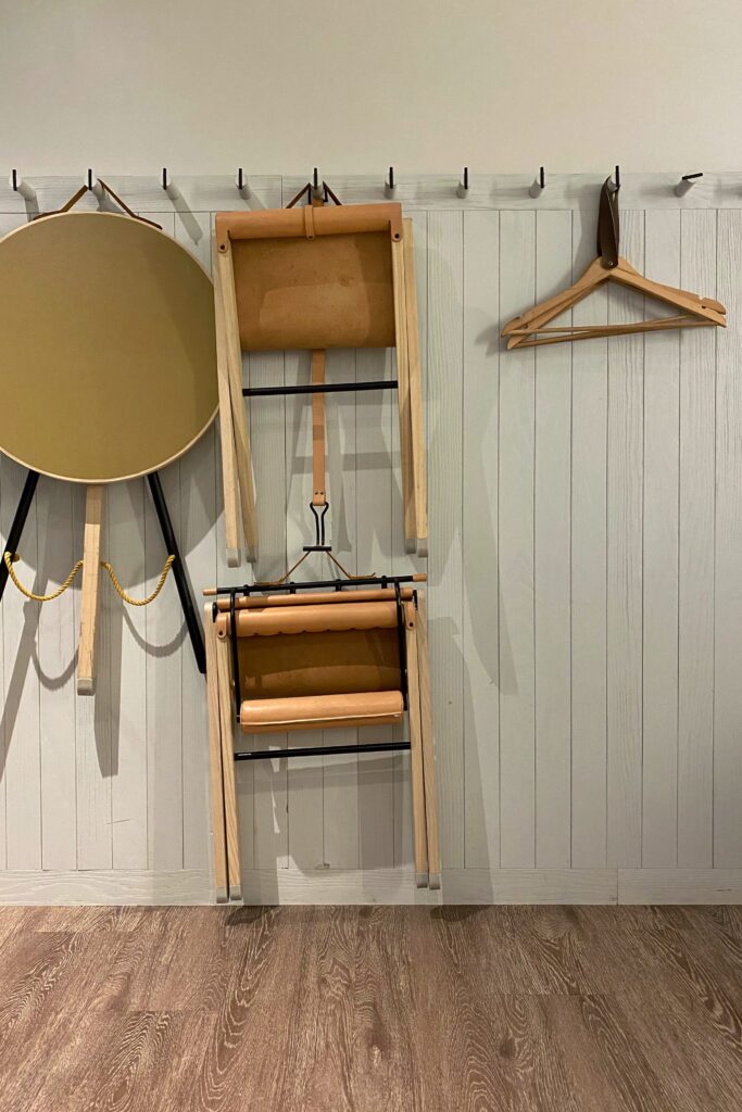 Wall-mounted folding chairs and circular table with leather and wood detailing in Moxy Times Square hotel room, illustrating smart compact living and stylish space-saving interior design in urban hospitality.