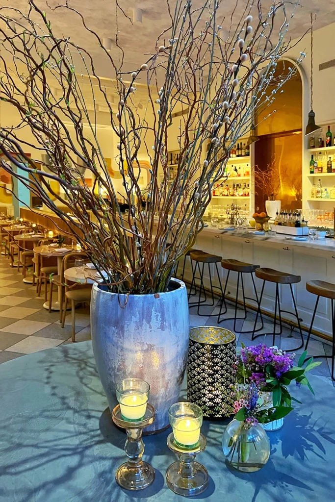 Il Fiorista restaurant interior in New York City featuring a marble bar, sculptural floral branches, candlelit tables, and warm neutral tones—an iconic biophilic, flower-filled dining space in Manhattan’s NoLIta neighborhood.